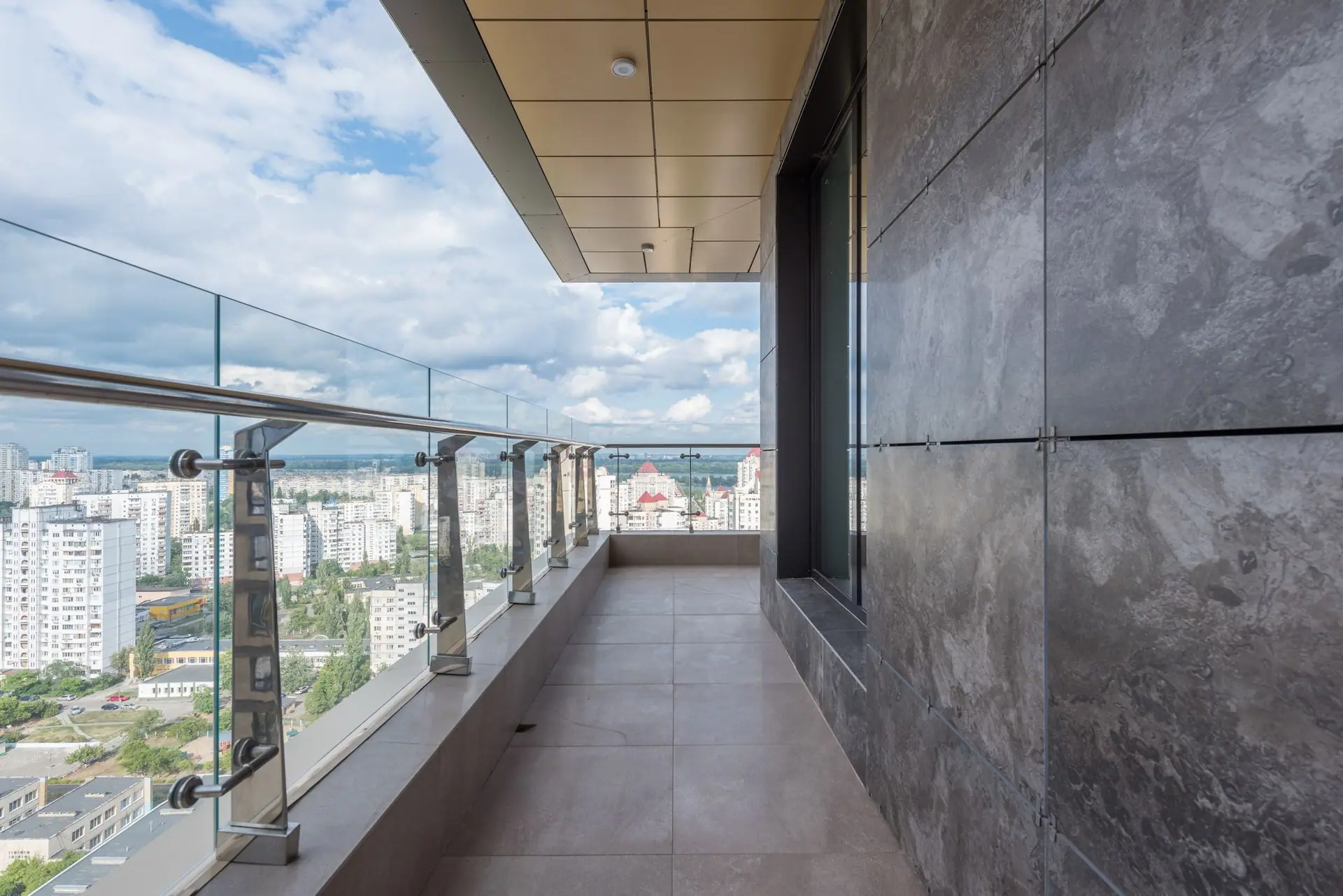 Frameless glass balcony railing on stainless steel posts overlooking the city